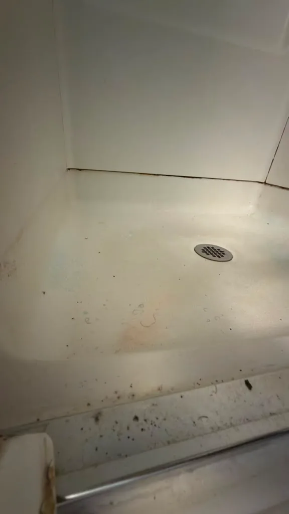 Shower base with staining in the corners before cleaning by Dolane Cleaning Services