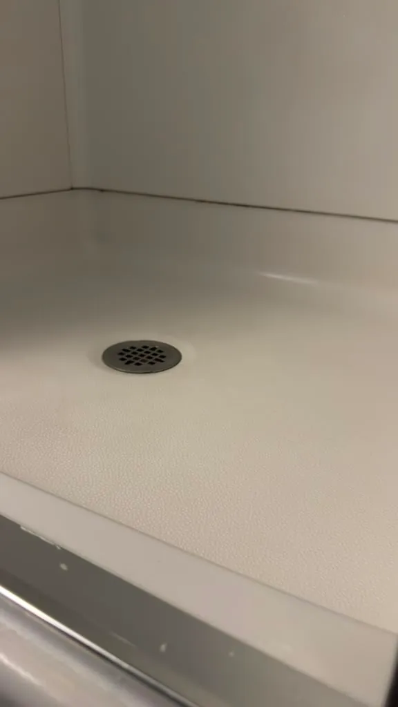 The same shower pan clean and clear after cleaning by Dolane Cleaning Services