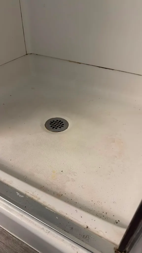 Shower pan with staining and build-up before cleaning by Dolane Cleaning Services